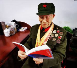 97岁抗战老兵夏锡生在翻阅《漠风吻过南飞雁》散文集